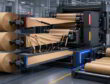 Three kraft paper parent rolls run through a converting line, showing defects in two rolls and smooth output in one.